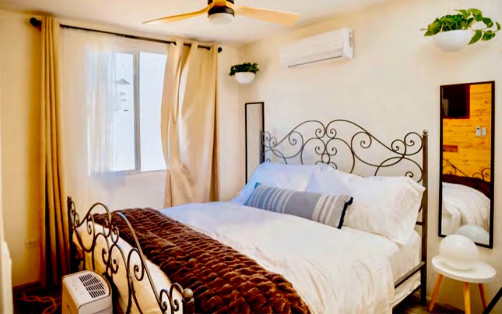 Habitación 02 de Casa Blanca con cama de herrería negra, ventilador de techo, minisplit y cortinas beige