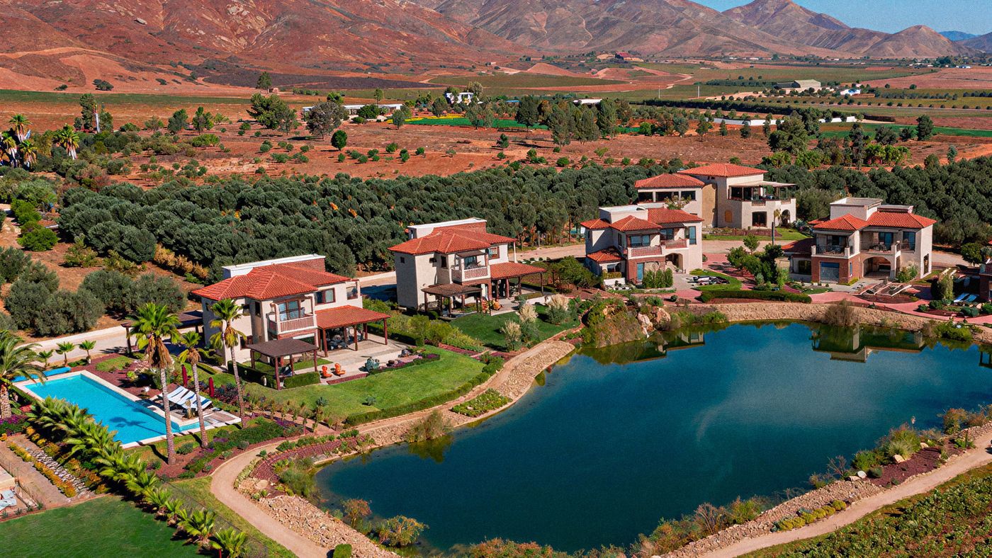 Vista aérea del Valle de Guadalupe con viñedos, casas y una presa entre montañas