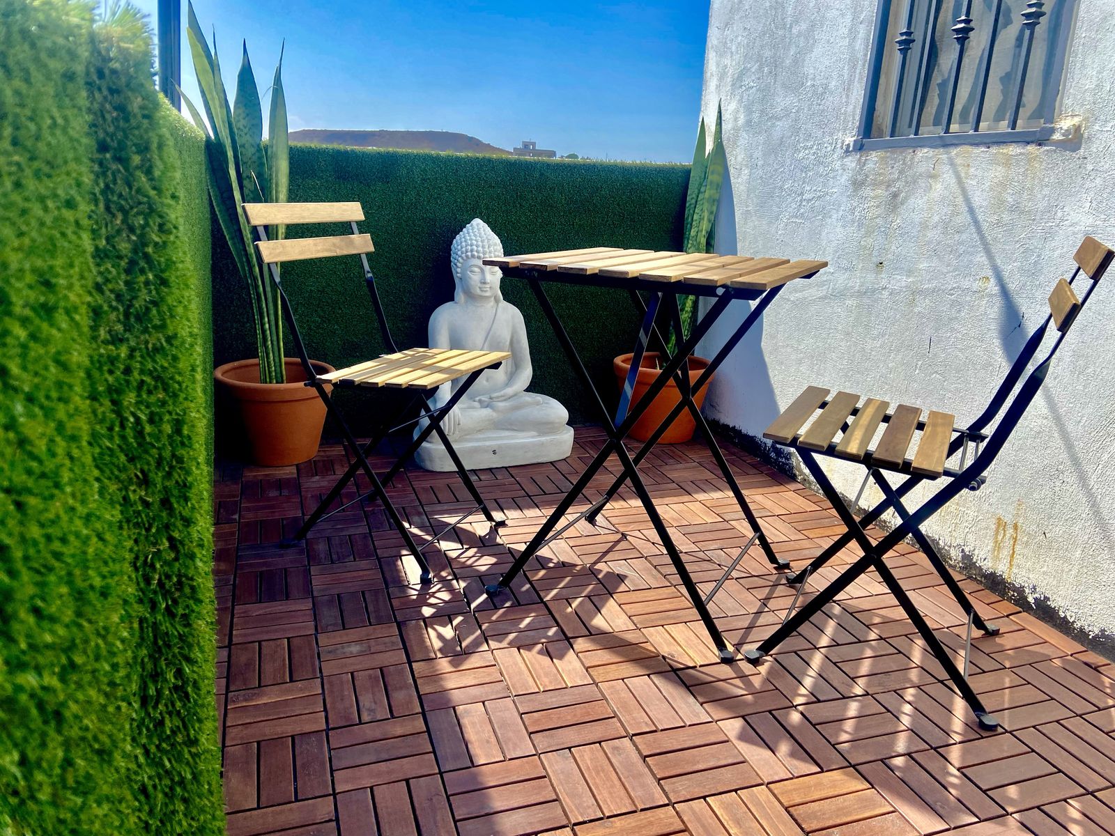 Balcón de la Habitación 01 de Casa Blanca con mesa, dos sillas y figura de Buda