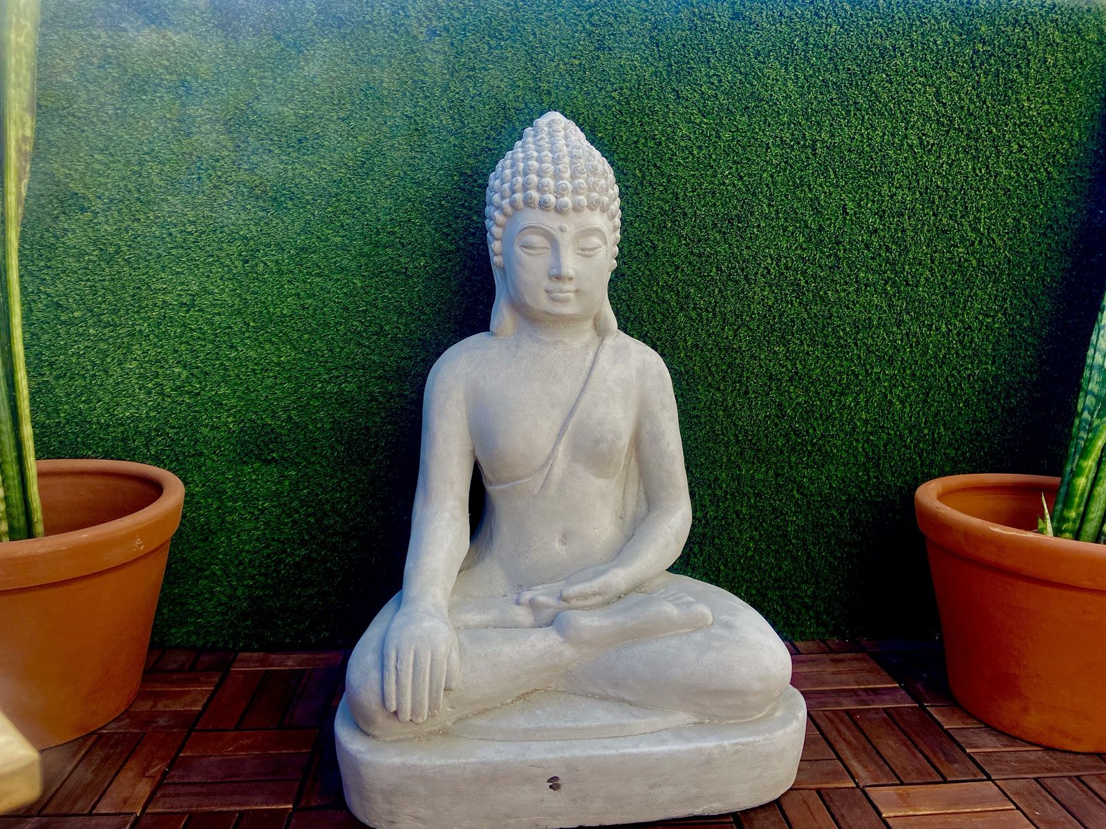 Figura de Buda de piedra blanca en el balcón de Casa Blanca junto a un muro verde