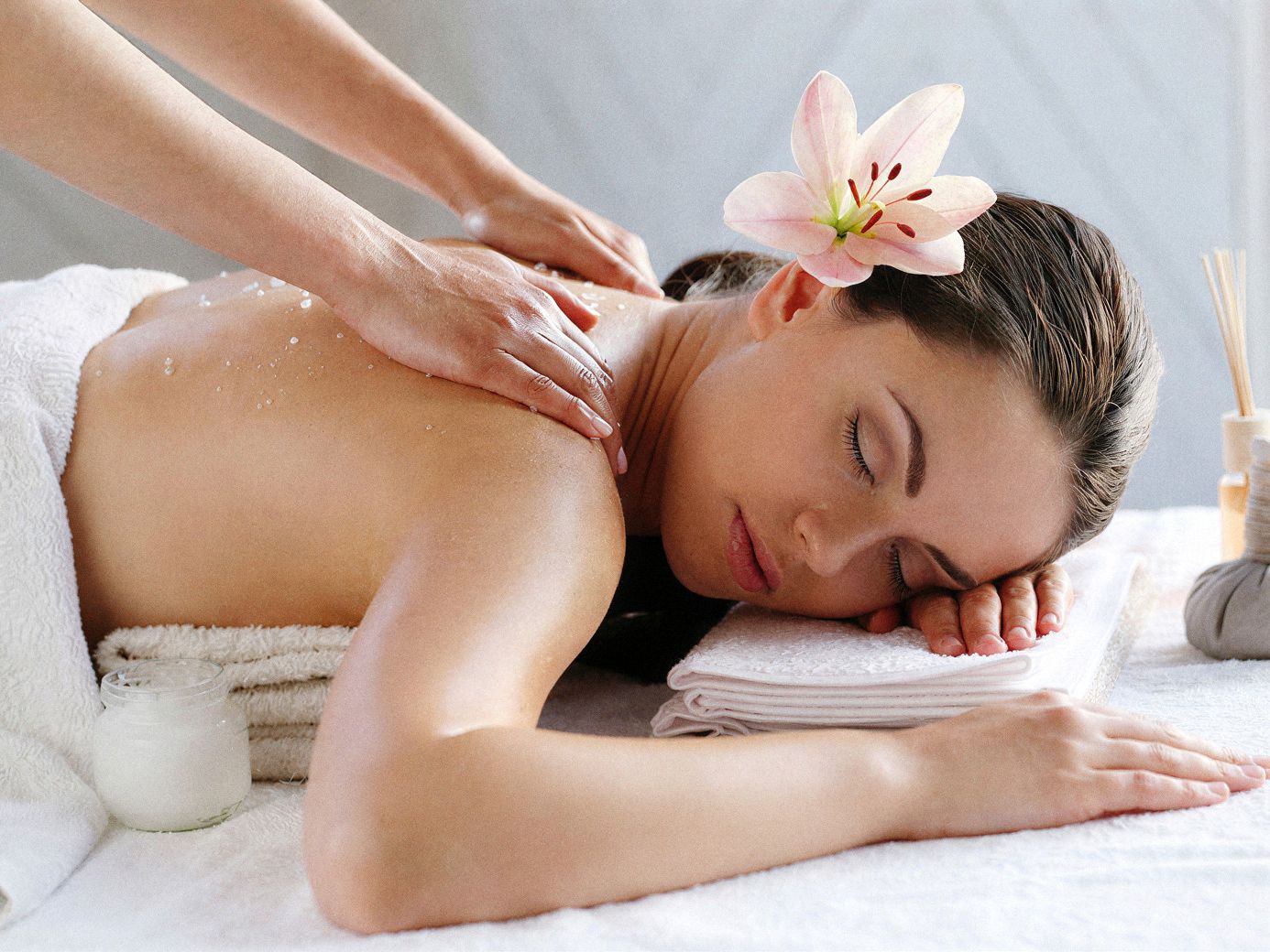 Masaje relajante de espalda con toalla blanca y flor en el cabello